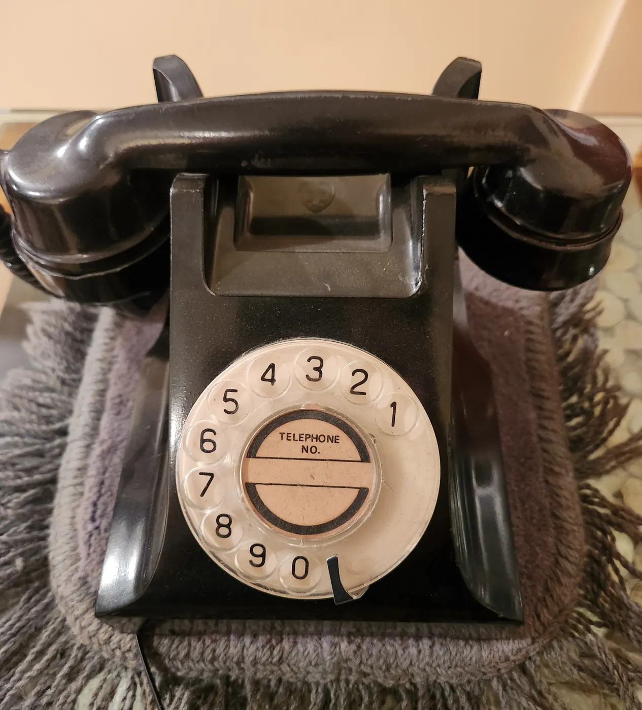 Czarny telefon tarczowy na stole. Oszustwo na wnuczka zaczyna się od nagłego telefonu i prośby o pieniądze albo tajemnicę.